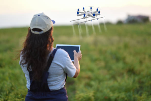 jeune agricultrice, pulvérisant ses cultures à l’aide d’un drone - aerial view mid air farm field photos et images de collection