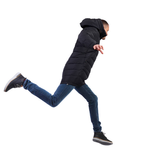 vista laterale di un uomo con una giacca invernale che salta. - strutting foto e immagini stock