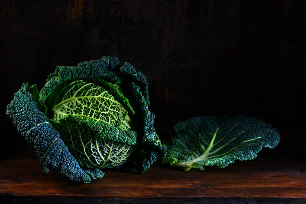 istock green savoy cabbage, whole head and a leaf on dark and moody rustic wood with copy space 1128103882