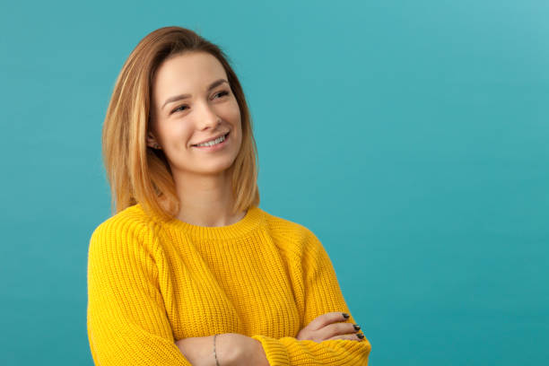 Studio portrait of an attractive 20 year old woman Studio portrait of an attractive 20 year old woman in a yellow sweater on a blue background top honor stock pictures, royalty-free photos & images