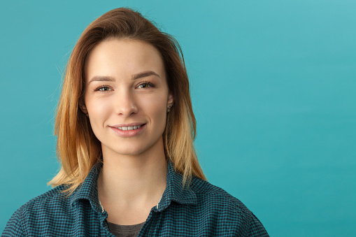 Studio portrait of a 20 year old attractive woman with dyed hair in a blue shirt on a blue background