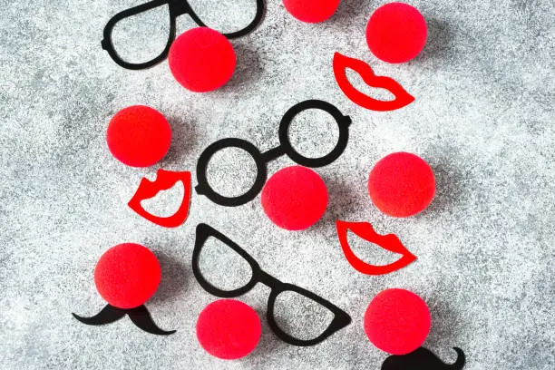 Red Nose Day, red noses with glasses, moustache on grey background. Toned deep negative.