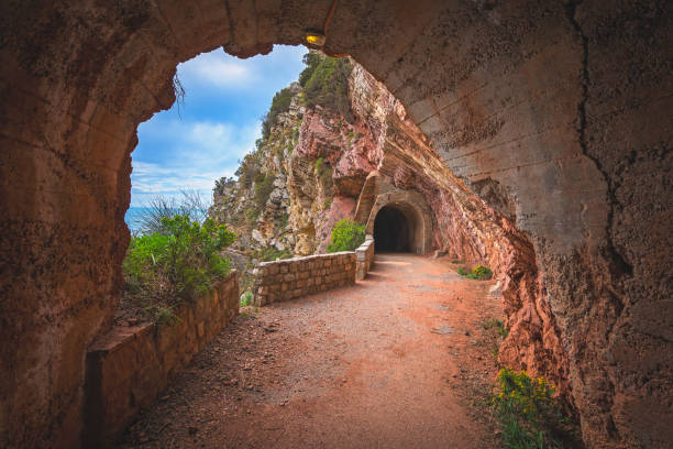 Tunnel cut out in the seaside rocky cliffs on the walking path in Petrovac bay, on the coast in Montenegro