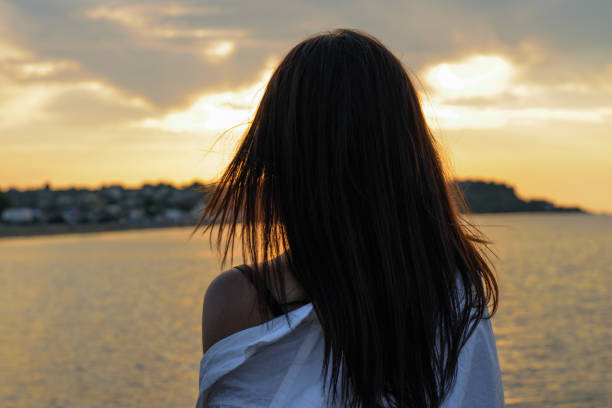 istock attractive brunette admires the beautiful sunset, dawn on the waterfront 1128111719