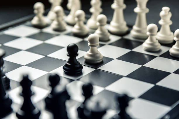 istock Chess board with black and white chess facing each other. White and black pawns go on the attack 1128117240