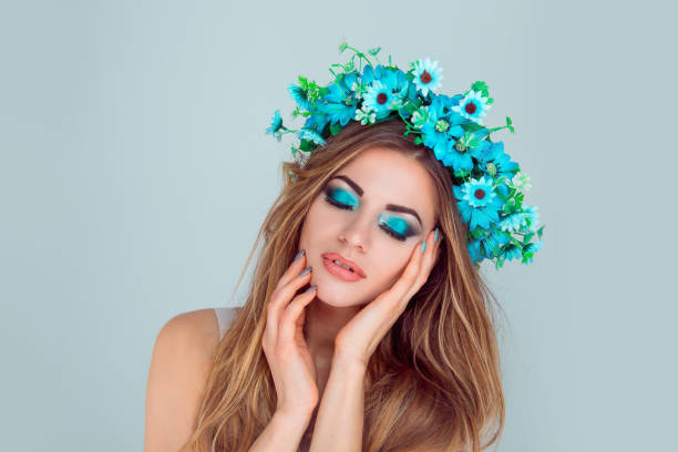 istock woman smiling posing with flowers on head blue eyeshadow closed eyes 1128119264