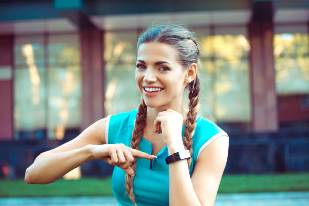 woman dressed in blue shirt sportswear pointing at  her smartwatch showing the route she run stock photo
