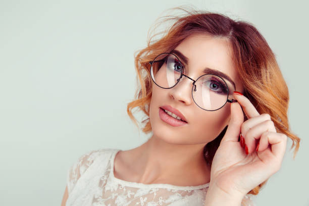 Curly blonde young European woman holding round glasses. stock photo