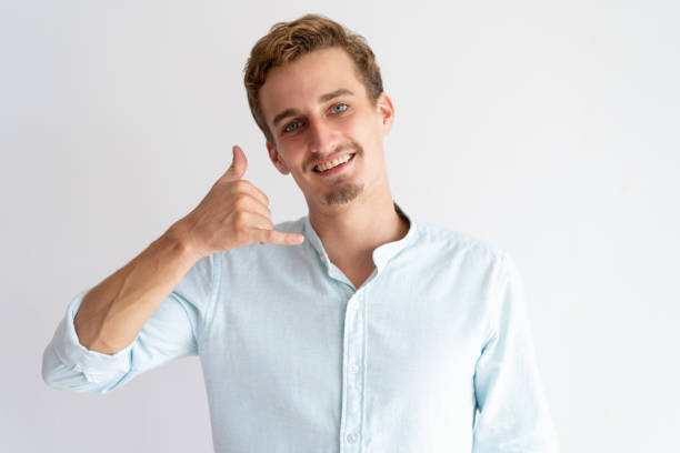 istock Smiling man making call me gesture and looking at camera 1128134640