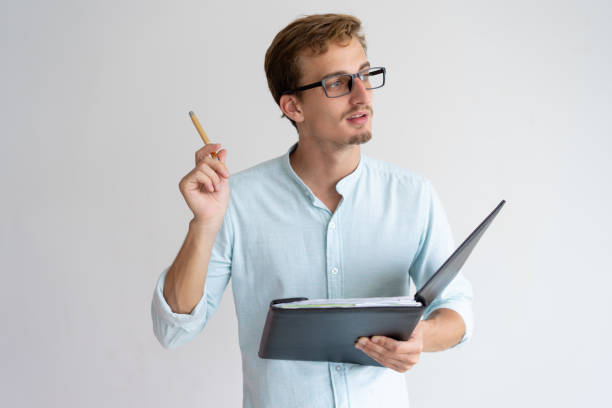 istock Thoughtful young man holding file, pen and having idea 1128134647