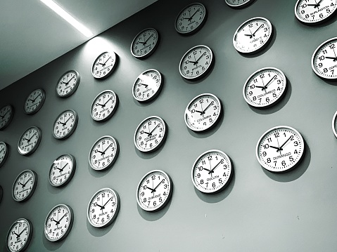 Many clocks on a wall for cities around the world