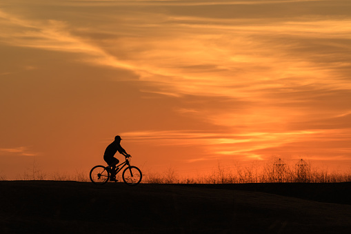 A person riding a bike during sunset.