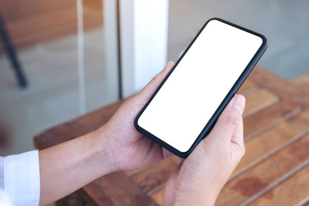 istock a hand holding black mobile phone with blank white desktop screen 1128153024