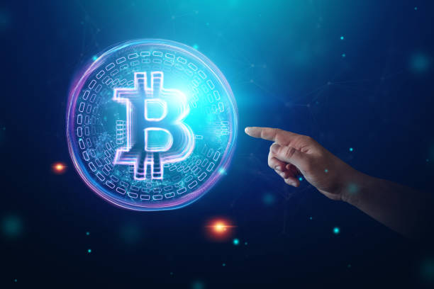 istock Male hand clicks on a bitcoin hologram, ultraviolet creative background. Cryptocurrency, electronic money, blockchain technology, finance, copy space. 1128153239