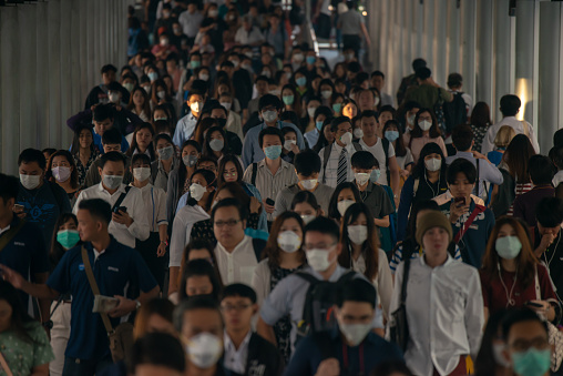 Group of many salary man wearing face mask for protect micro dust in air while going to their workplace during pm2.5 air pollution crisis in Bangkok at moring rush hour.