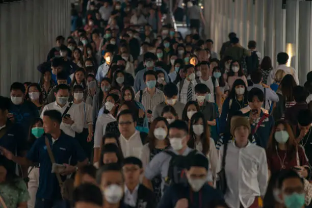 Photo of Group of many salary man wearing face mask for protect micro dust in air while going to their workplace during pm2.5 air pollution crisis in Bangkok at moring rush hour.