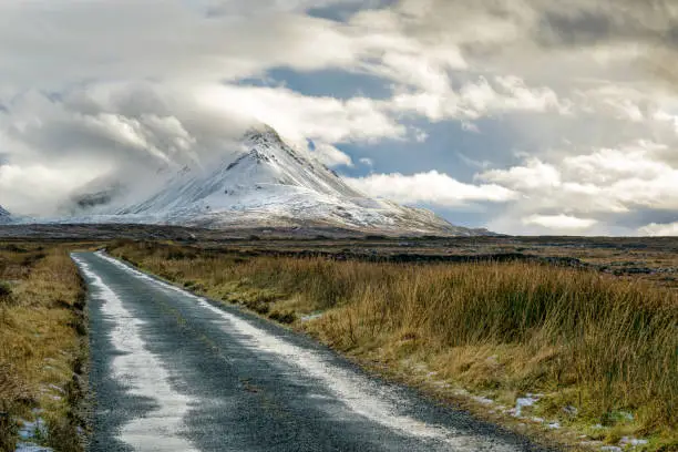 Picture of a remote mountain road going to the snow covered Errigal mountain in Donegal Ireland.