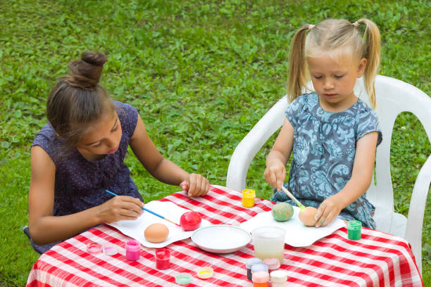 istock Preparing for the Easter. Two kids painting Easter eggs outdoors 1128165996