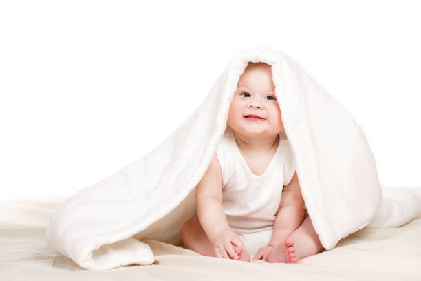 istock Cute baby peeking out from under the blanket,playing on the bed. 1128166818
