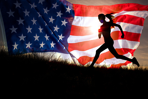 Running woman. Female runner training celebrating the 4th of july on marathon with waving american flag