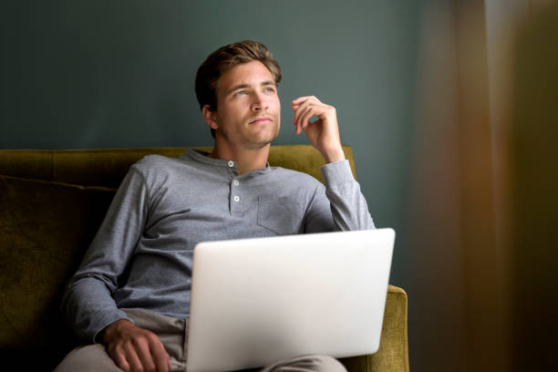 istock Thoughtful man with laptop sitting on sofa 1128175293