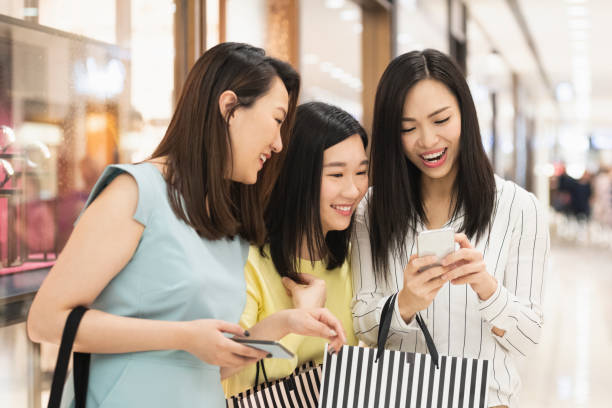 istock Female friends looking at phone while shopping 1128175821
