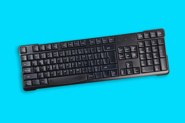 istock One black plastic wireless computer keyboard in center of blue office table. Top view. Business concept 1128181035