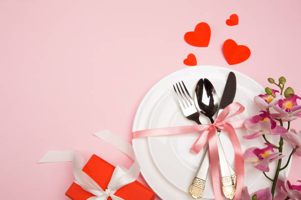 istock Festive table setting for Valentine's Day with fork, knife,  hearts on a red background. Top view. - Image 1128181159