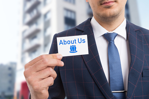 Businessman holding white card with about us icon as more information concept