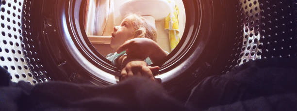 istock Little Girl looking in washing machine 1128182740