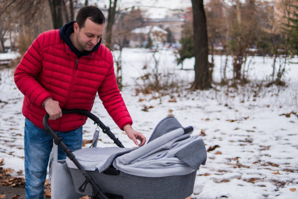 istock Man is walking with a baby in a stroller in the park 1128183487