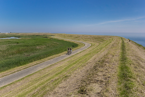 Texel, Netherlands - June 07, 2018: Couple on bicycles along a dike on Texel island, Netherlands