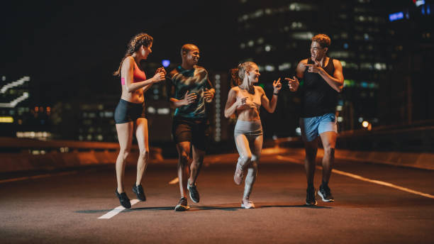 runners training together outdoors in evening - night running imagens e fotografias de stock