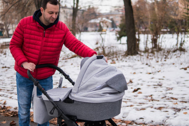 istock Man is walking with a baby in a stroller in the park 1128185900