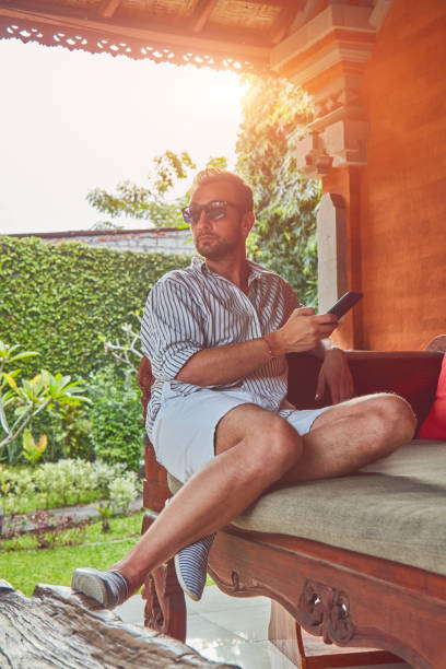 istock Man using smart phone on a terrace sofa in summertime. 1128185925