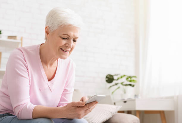 istock Cheerful aged woman using her smartphone at home 1128190404