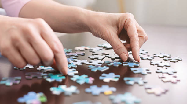 elderly woman hands doing jigsaw puzzle closeup - hobbies imagens e fotografias de stock