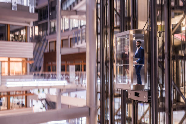 istock Young businesspeople talking in elevator. 1128191160