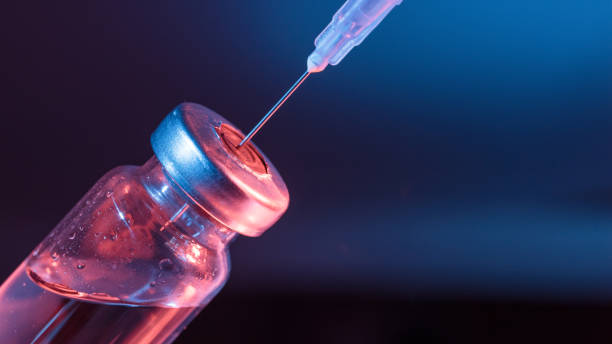 istock Injection vial with syringe needle on blue background 1128196217