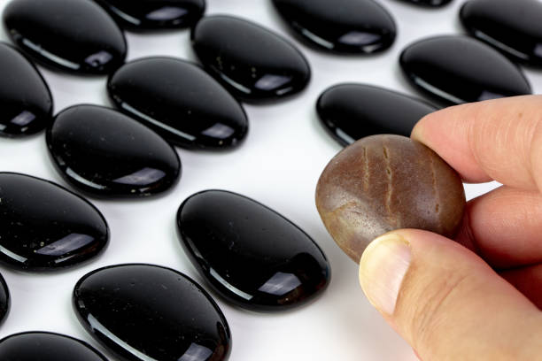 istock Black pebbles on white background with brown pebble. 1128198242