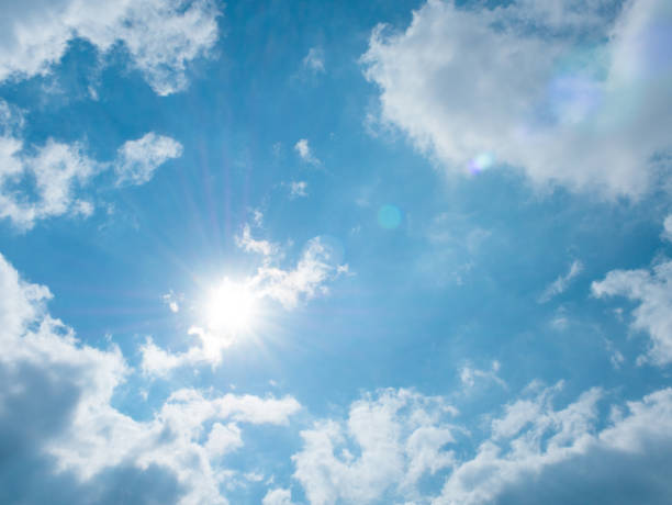 istock Shining sun and clouds on blue sky background 1128198955