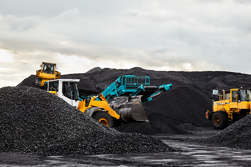 Tractores Caterpillar recoger la pila de carbón negro. Ilustración del campo de la fuente de la central eléctrica. photo