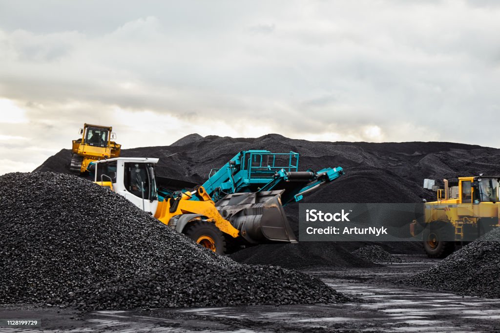 Caterpillar tractors collect black coal pile. Illustration of supply field of power station. Coal Stock Photo