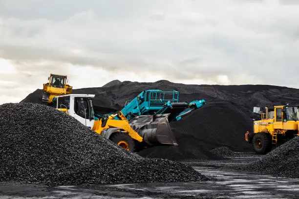Photo of Caterpillar tractors collect black coal pile. Illustration of supply field of power station.