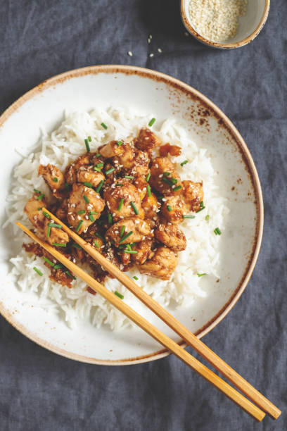 istock Top view on sesame chicken pieces with rice on a ceramic plate. Chinese traditional dish. 1128199966