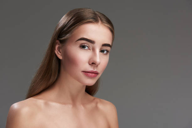 istock Beautiful young lady standing against gray background 1128203396