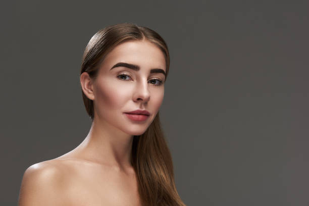 istock Charming young lady with naked shoulders standing against gray background 1128203424