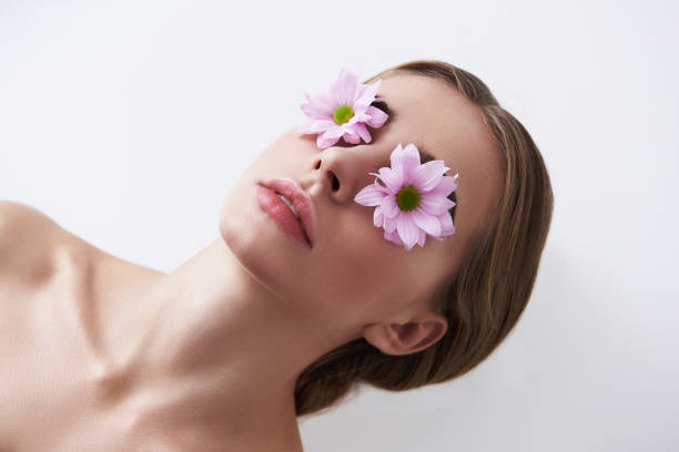 istock Beautiful young lady with flowers on her eyes lying on white background 1128203468