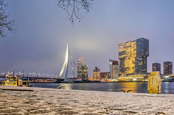 Rotterdam, The Netherlands, February 1, 2019: view from Willems quay, covered with a thin layer of snow, across Nieuwe Maas river towards Erasmus bridge and De Rotterdam building
