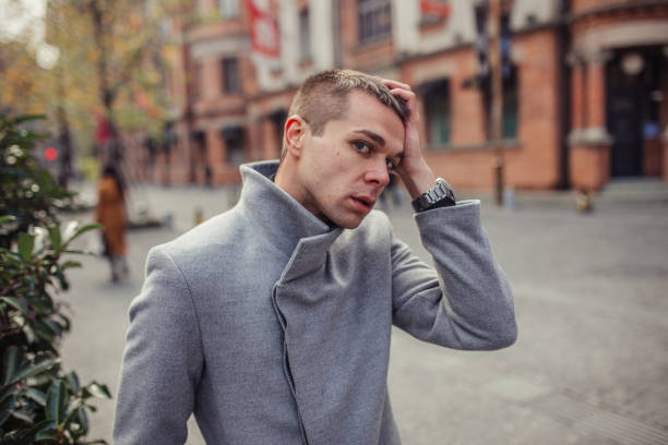 istock Man in gray coat touching his head 1128211887